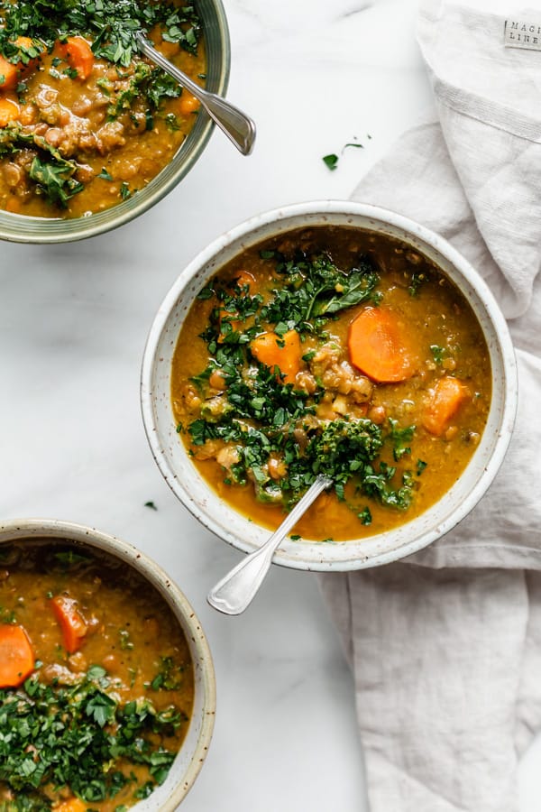 three bowls of lentil soup with spoons in them