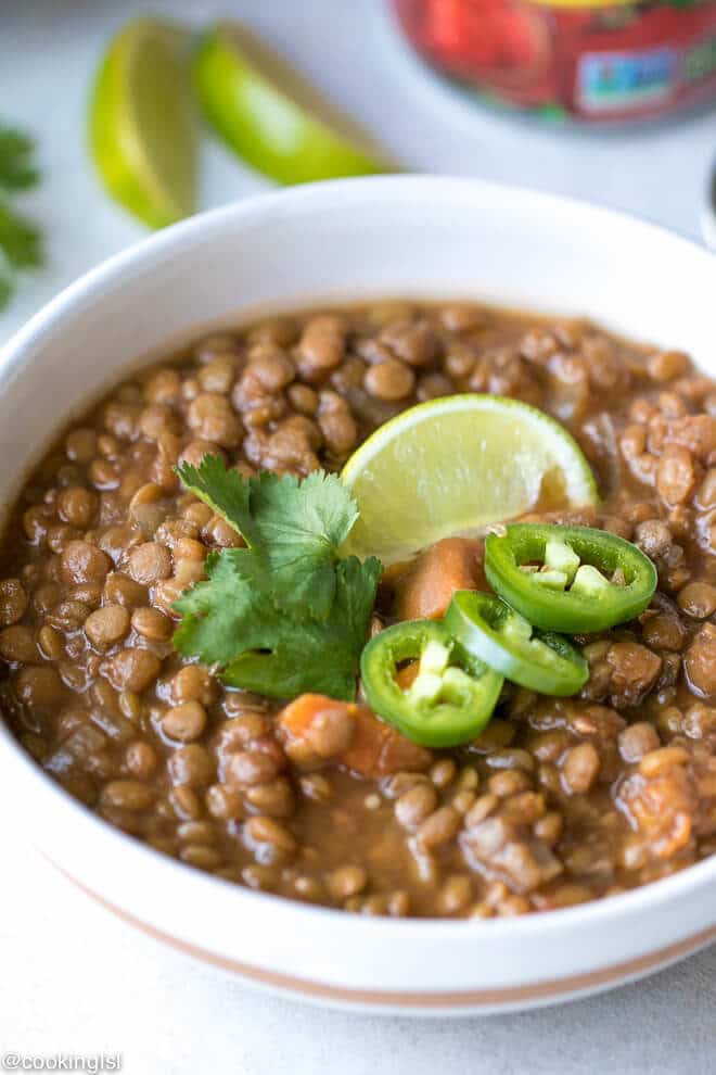 Sweet Potato Lentil Chili Recipe - a porcelain bowl with lentil soup garnished with cilantro, lime and jalapeños.