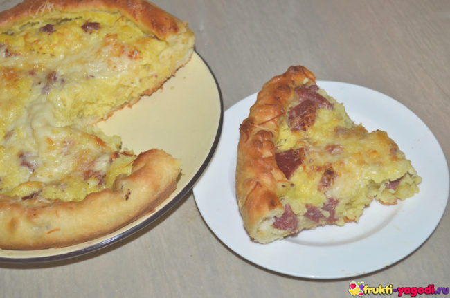 Отрезанный кусок дрожжевого пирога с картошкой и колбасой