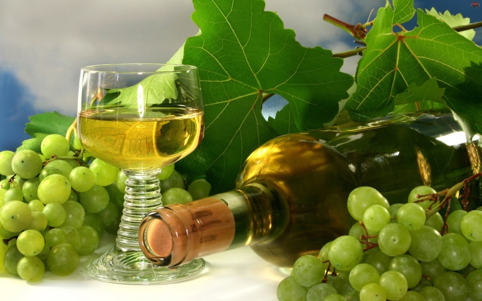Бокал, бутылочка белого домашнего вина, гроздь и листья винограда