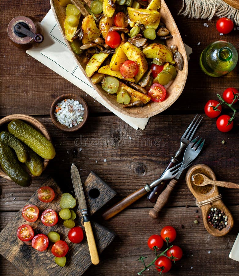 Delicious warm vegetable salad with baked potatoes, fried mushrooms, cherry tomatoes, pickles royalty free stock photo