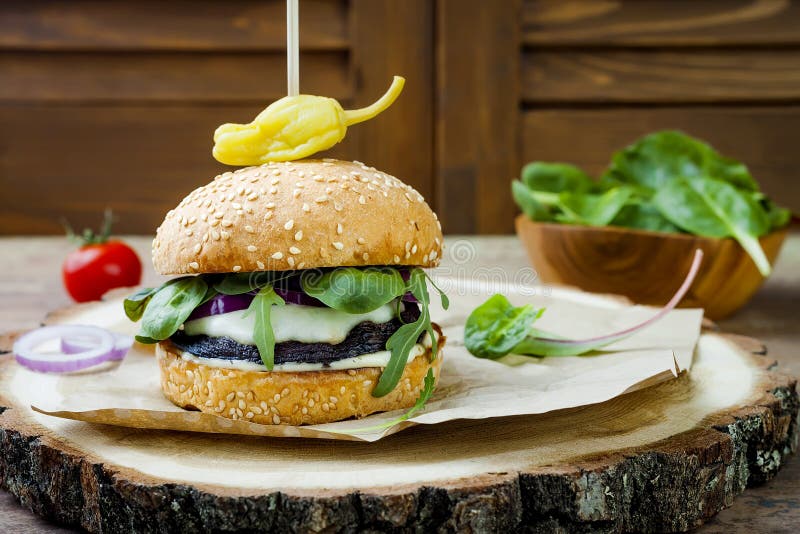 Grilled portobello mushroom burger. Healthy veggies hamburger with onions, arugula, cheese, spicy pickled hot peppers royalty free stock images