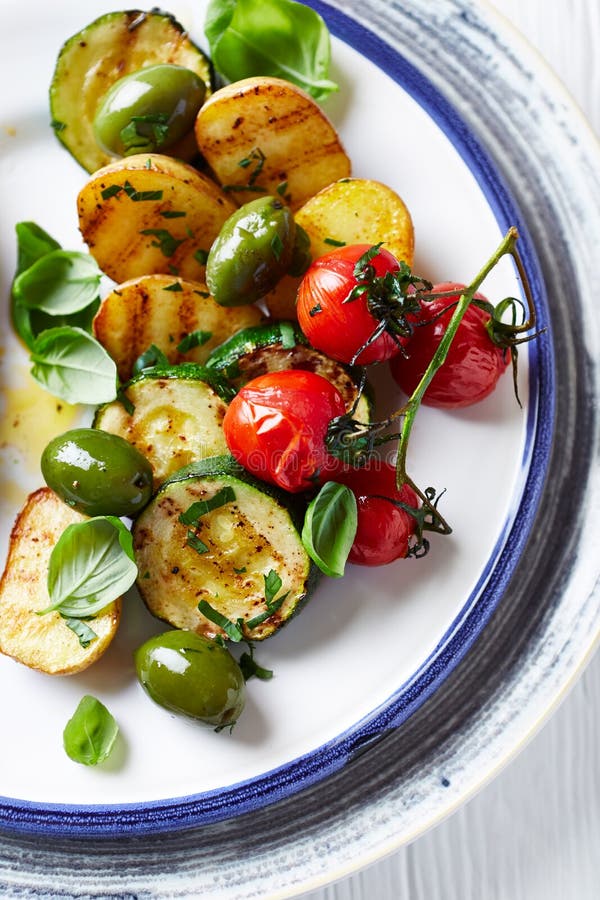 Soft grilled zucchini, potatoes and cherry tomatoes with olives stock photo