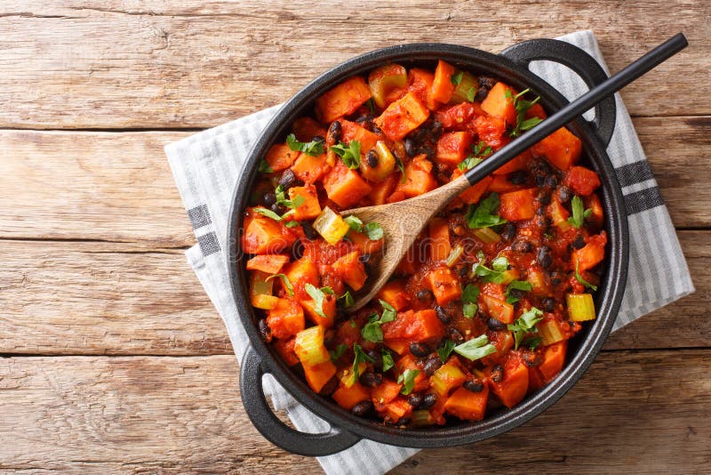 Traditional recipe for chili sweet potatoes and black beans with tomatoes, celery close-up in a pan. Horizontal top view royalty free stock photo