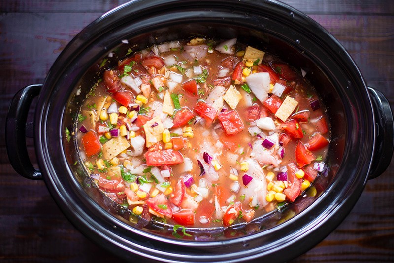 Overhead of the slow cooker with all the ingredients for the slow cooker chicken tortilla soup having been mixed together, and ready to be covered and cooked on low until ready to serve.