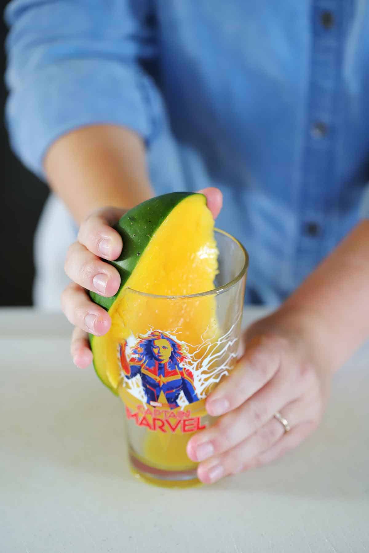Using a pint glass to peel a mango.
