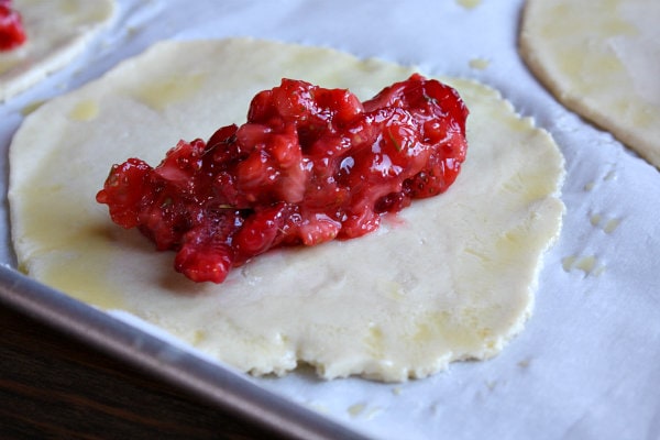 Berry Hand Pie dough on a baking sheet with berries in the middle of the rolled out round of dough