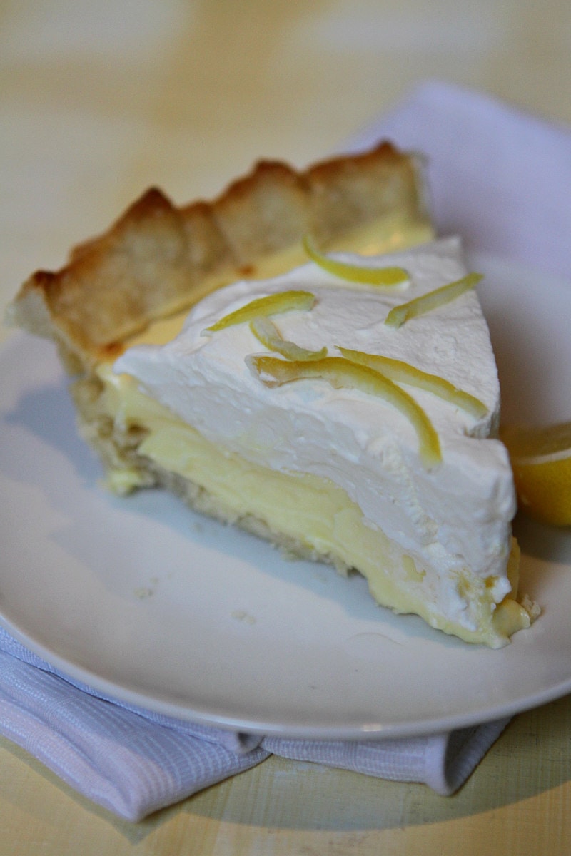 slice of Lemon Sour Cream Pie on a white plate set on a white napkin