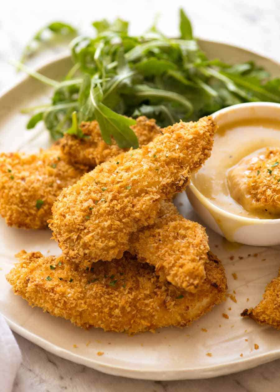 Crunchy Baked Chicken Tenders piled on a plate with a side of Honey Mustard Dipping Sauce, ready to be eaten