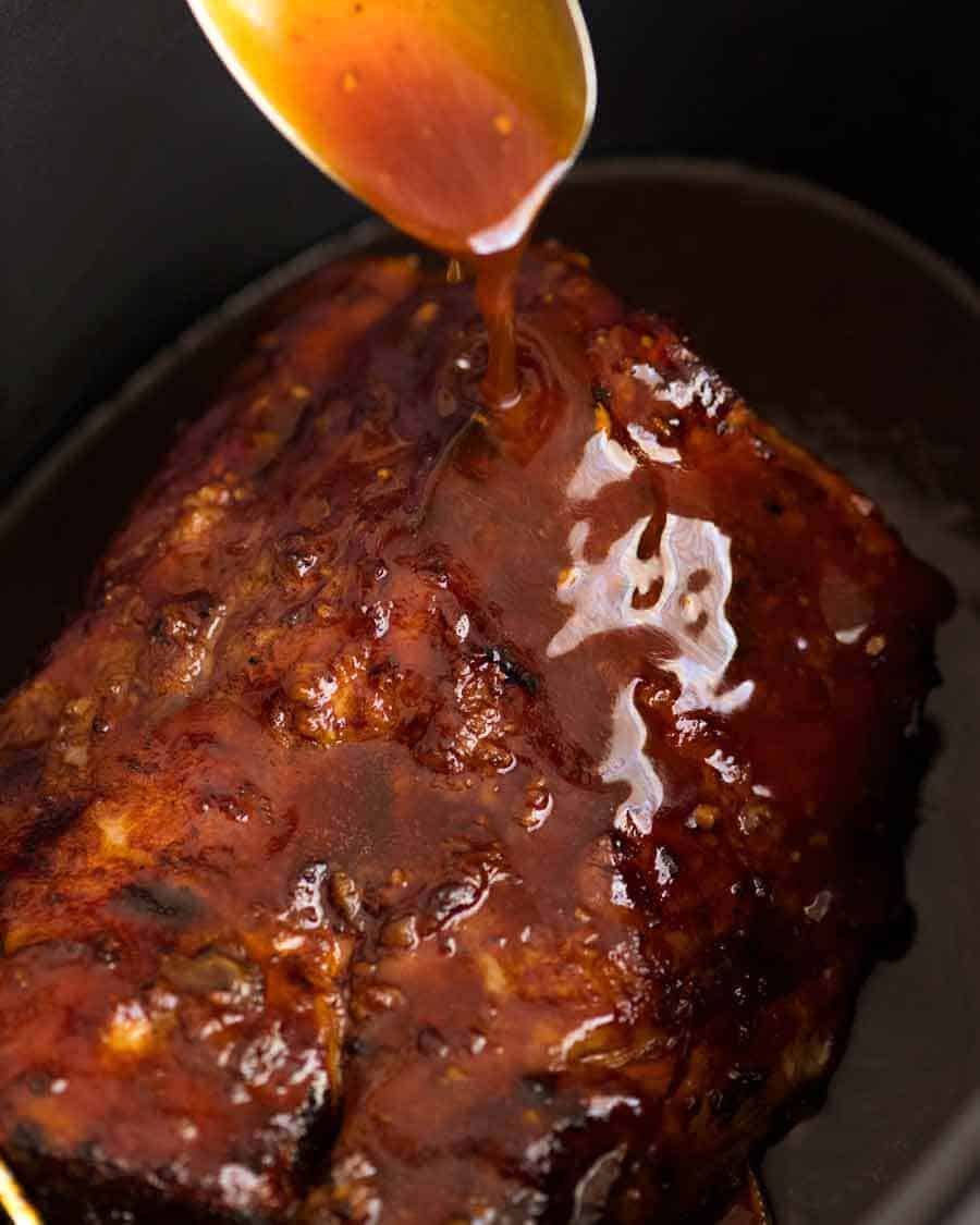 Slow Cooker Pork Loin Roast in a crock pot with a spoon drizzling honey butter sauce over it
