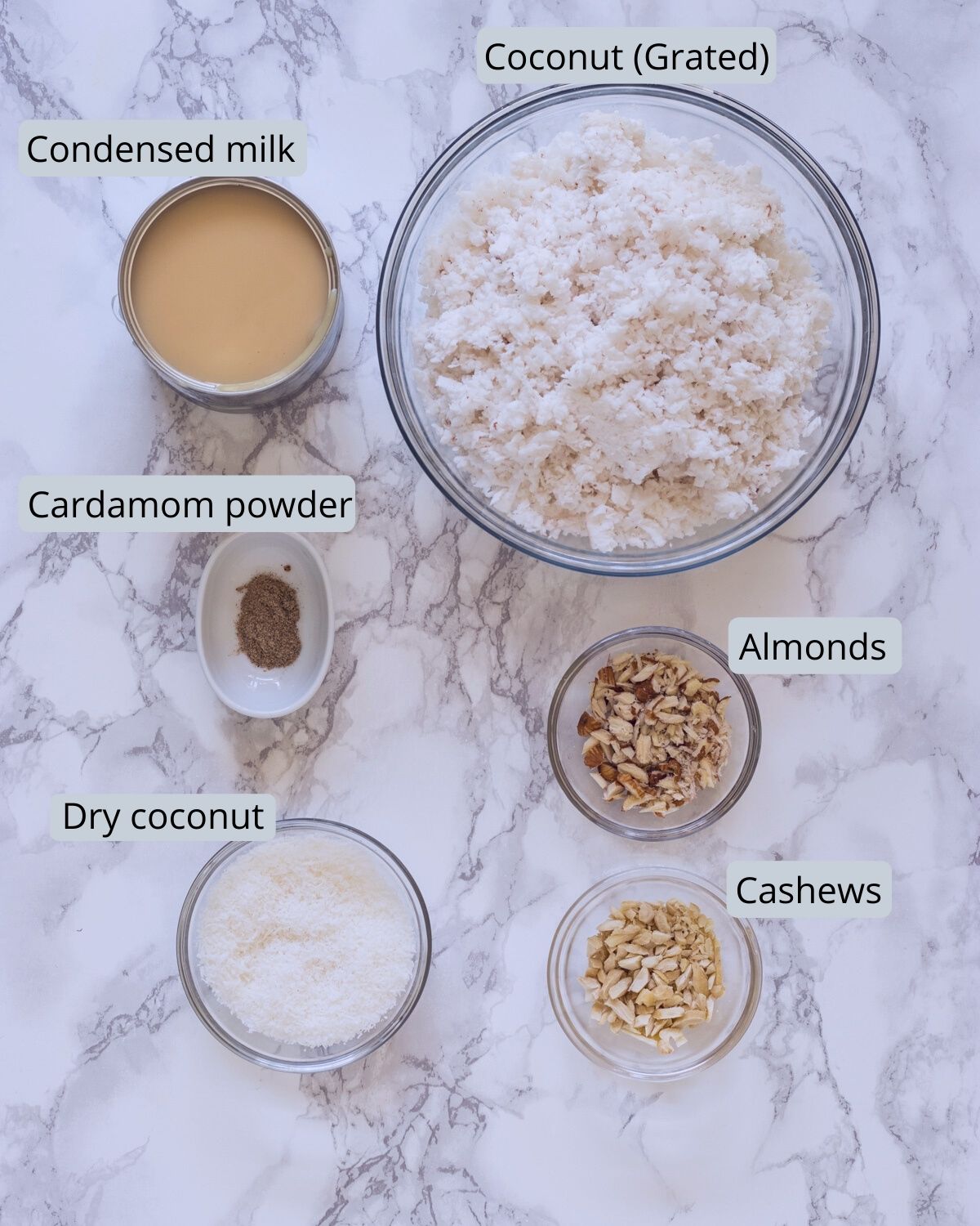 image of ingredients used for coconut ladoo. Includes coconut, condensed milk, cardamom, nuts, dry coconut.