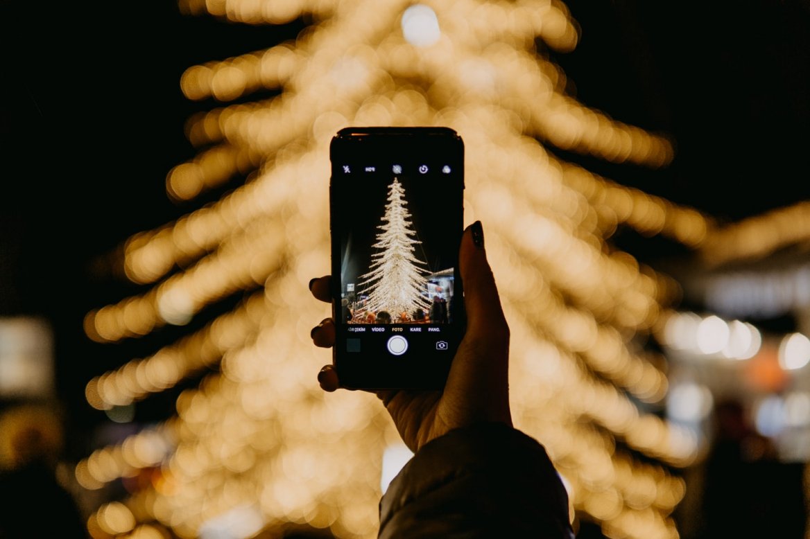 Человек фотографирует новогоднюю елку