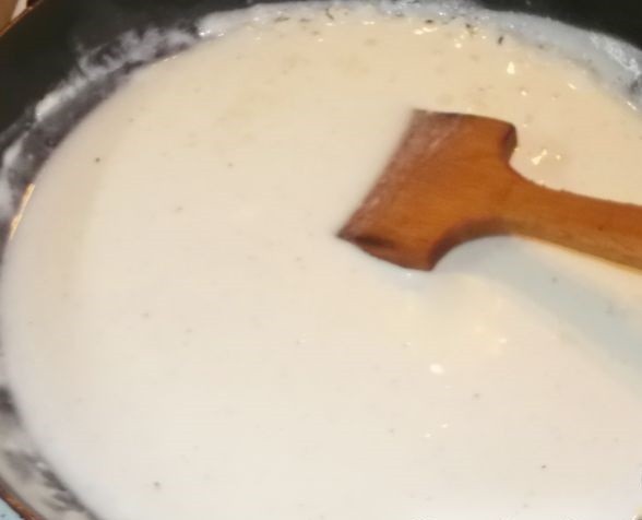белый соус в сковороде с деревянной лопаткой
