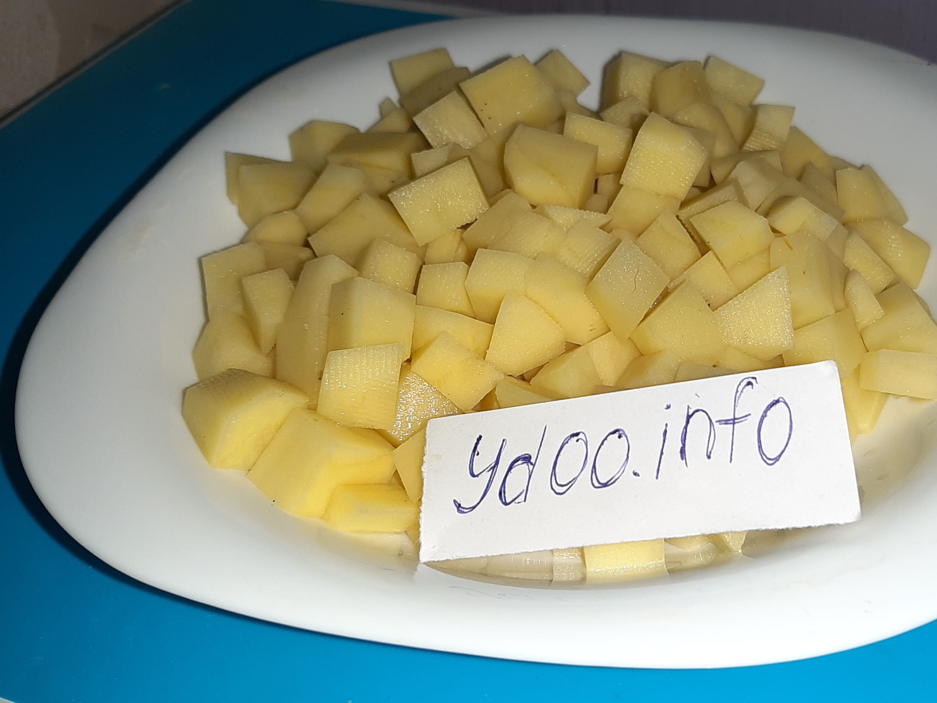 нарезанный кубиками картофель в белой тарелке на столе