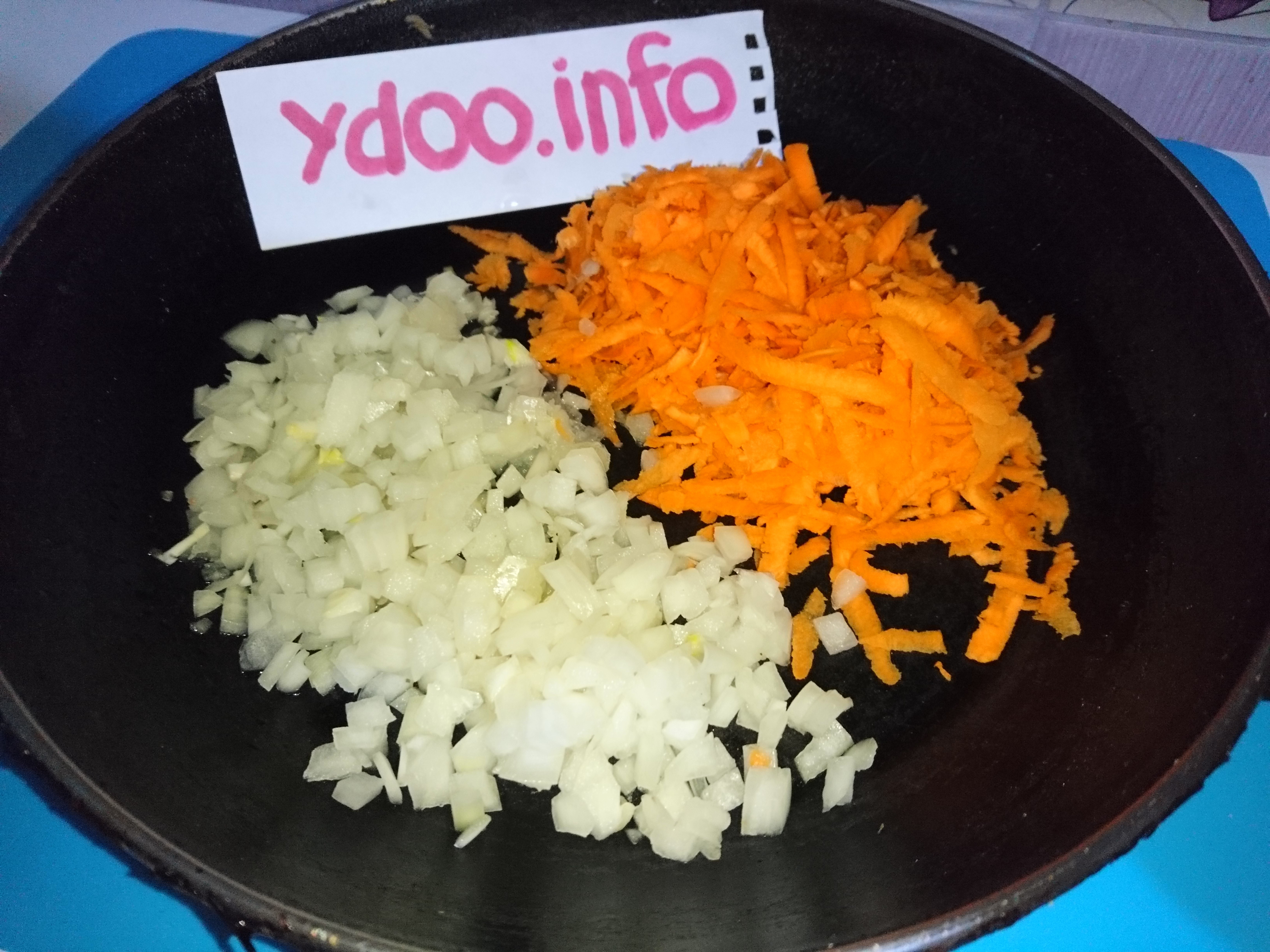 нарезанные репчатый лук и морковь в сковороде на столе