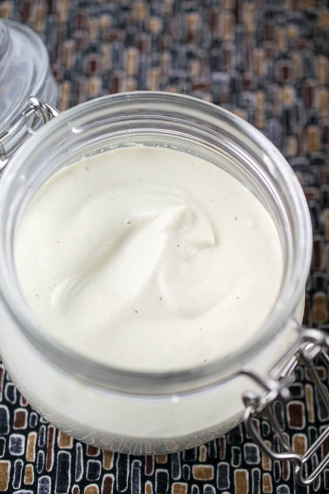 Oil-free vegan mayonnaise in a glass jar, with the surface of the mayonnaise slightly agitated to show the texture